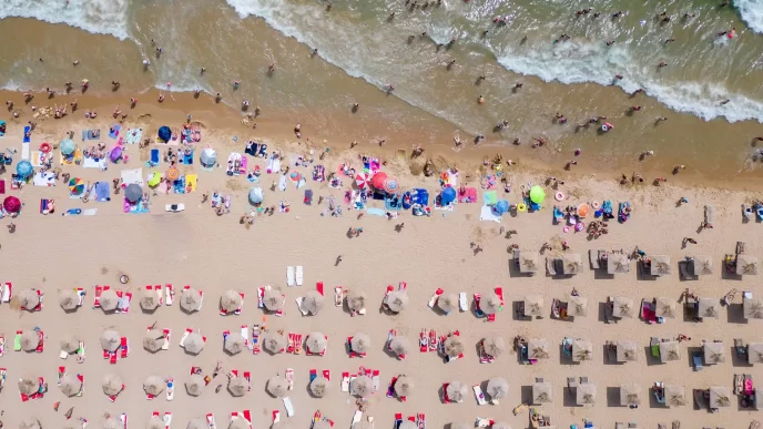Vista dall'alto di una spiaggia affollata con ombrelloni e bagnanti.