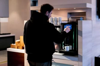 Persona che usa una macchinetta del caffè in un'area colazioni.