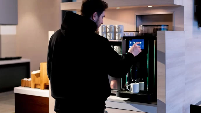 Persona che usa una macchinetta del caffè in un'area colazioni.
