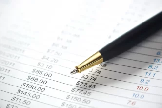 Primo piano di una penna su un foglio di calcolo con valori in dollari.