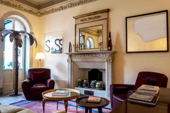 Sala lettura con camino, poltrone e decorazioni eleganti in un albergo a Pietrasanta.
