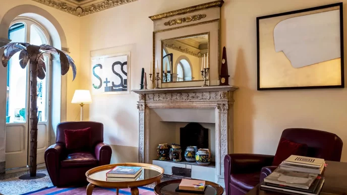 Sala lettura con camino, poltrone e decorazioni eleganti in un albergo a Pietrasanta.