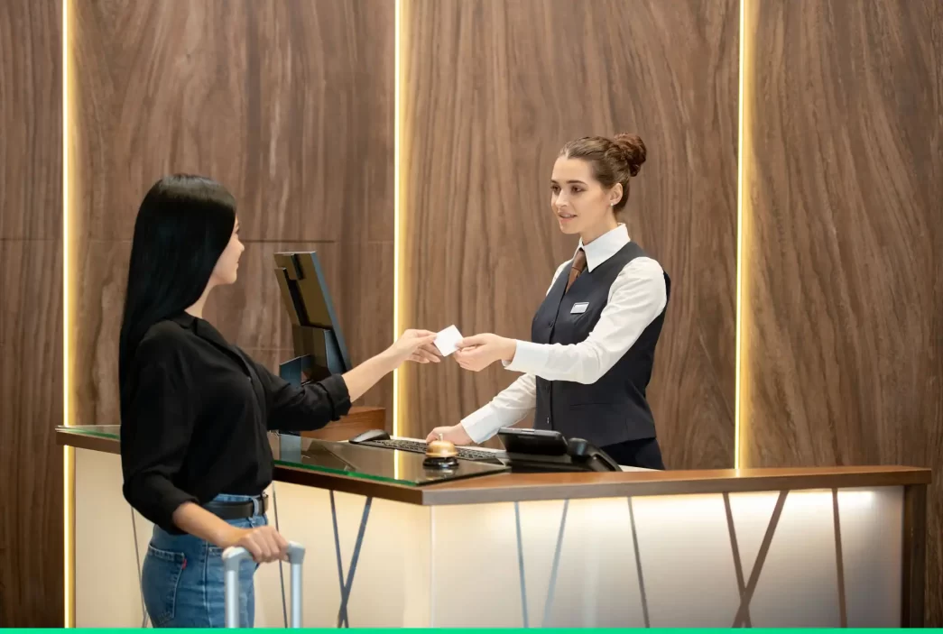 Cliente alla reception di un hotel riceve una chiave dalla receptionist.
