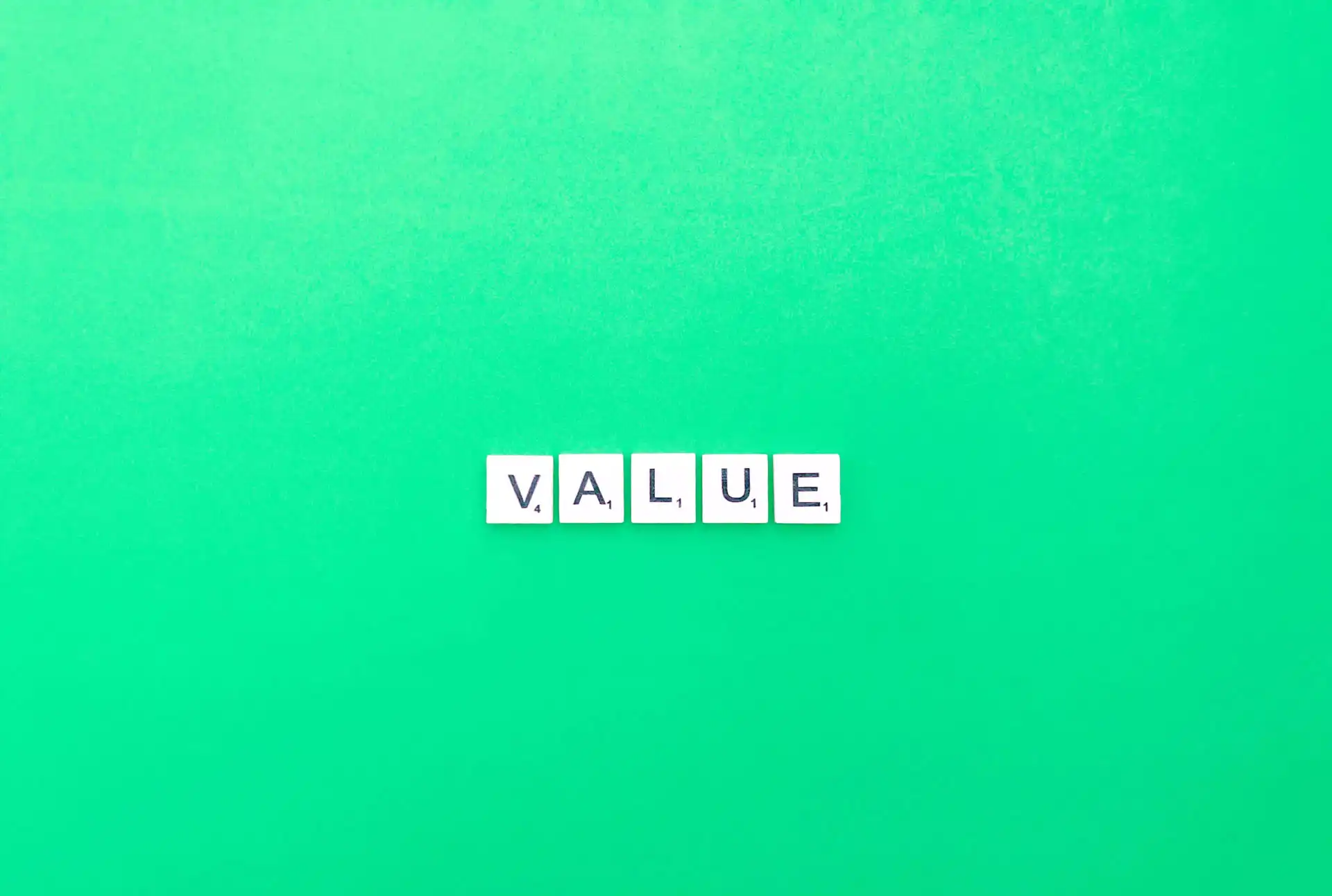 Parola 'VALUE' formata da lettere Scrabble su sfondo verde.