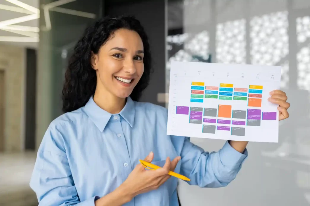 Donna sorridente che mostra un calendario colorato.