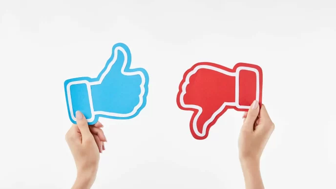 Immagine di due mani che tengono icone di like e dislike.
