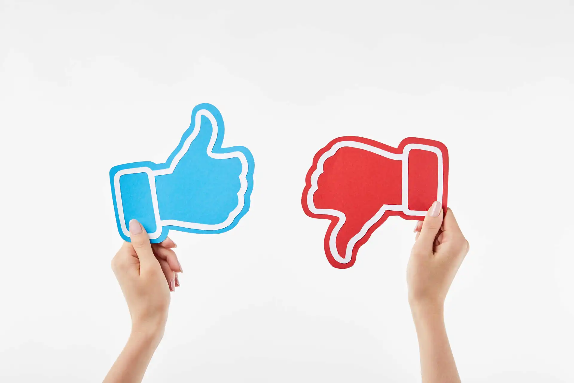 Immagine di due mani che tengono icone di like e dislike.