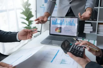 Discussione di analisi dati aziendali con grafici su laptop e documenti.