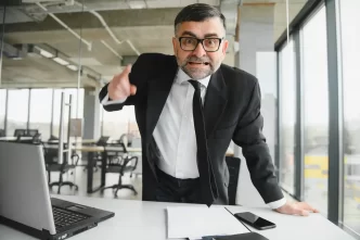Gestore di un hotel arrabbiato davanti a un laptop.