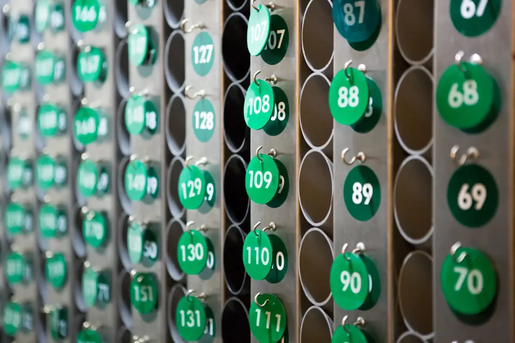 Raccolta di chiavi numerate per le camere di un hotel su un rack di metallo.