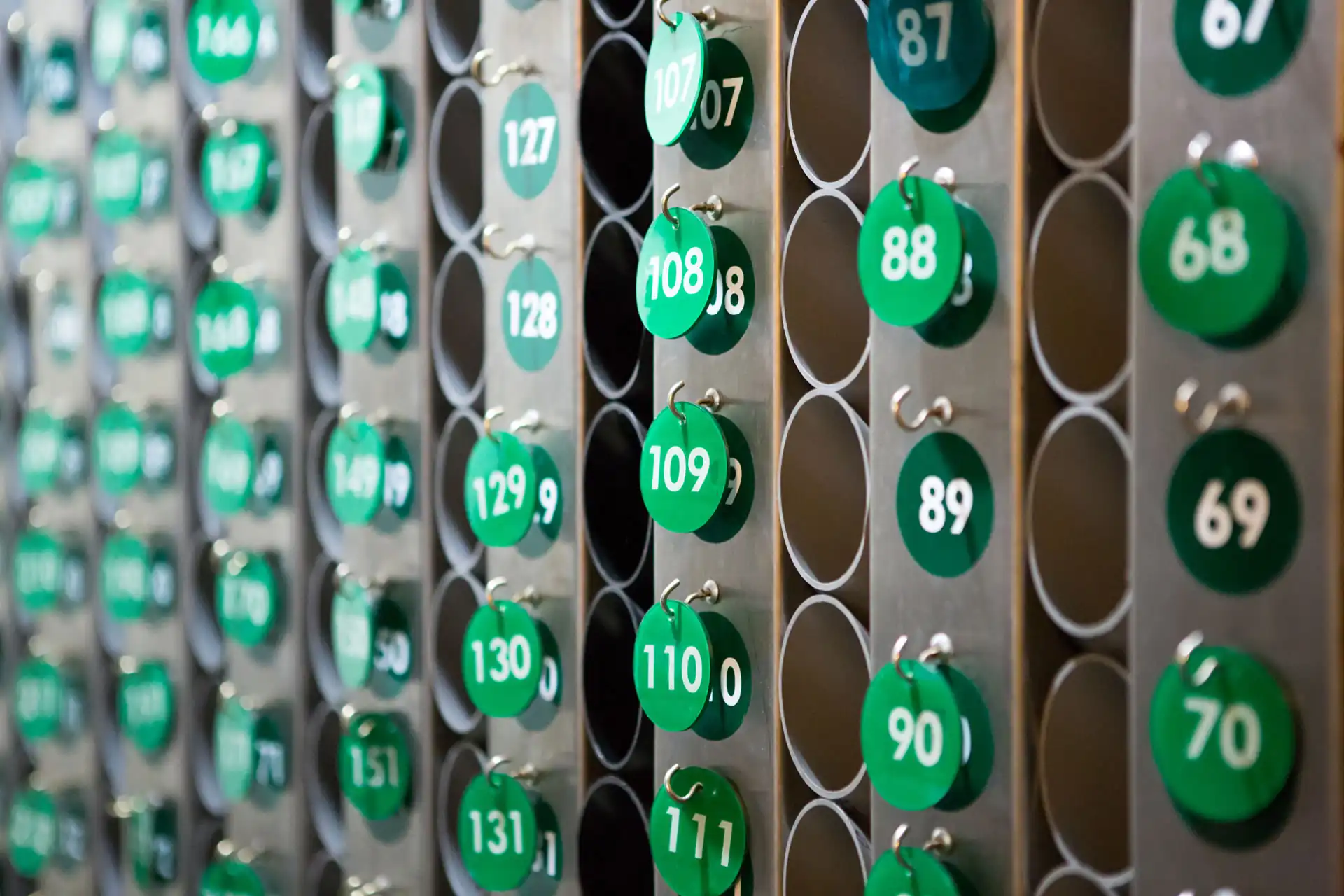 Raccolta di chiavi numerate per le camere di un hotel su un rack di metallo.