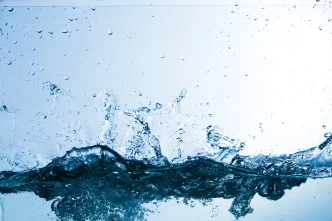 Gocce di acqua, spruzzi e schizzi su sfondo azzurro chiaro