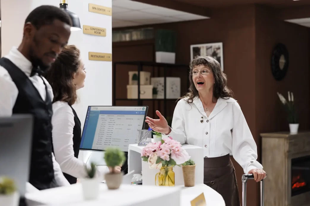 Reception di un hotel con personale accogliente e ospite sorridente, Up-selling in Hotel e front office.