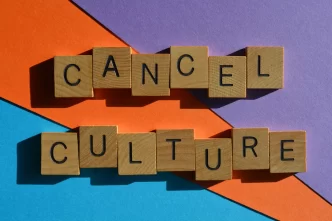 Immagine con scritta 'Cancel Culture' composta da lettere di legno su sfondo colorato arancione, blu e viola.