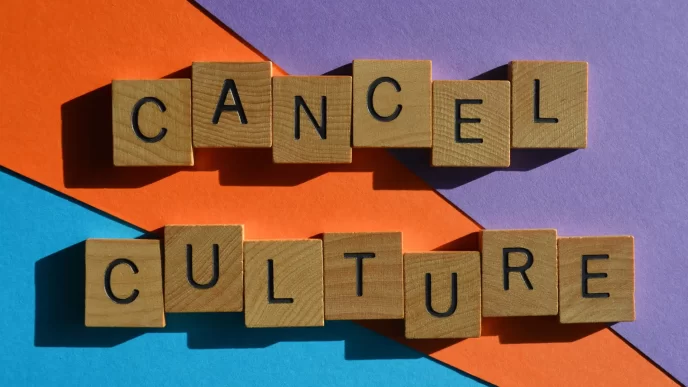 Immagine con scritta 'Cancel Culture' composta da lettere di legno su sfondo colorato arancione, blu e viola.