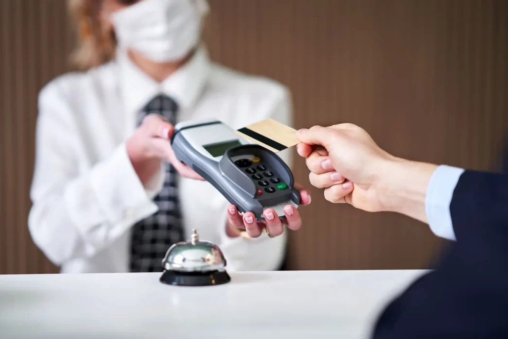 Psd2 Hotel: Receptionist in un hotel che gestisce un pagamento con carta di credito durante il check-in.