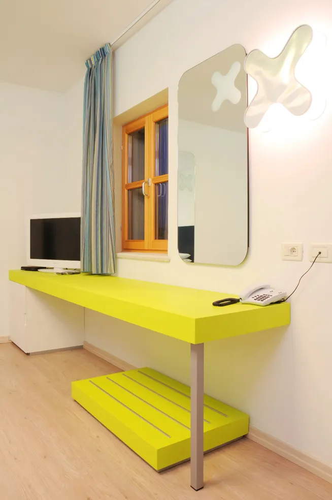  Area scrivania dell'hotel con arredamento giallo e finestra con tende a righe.