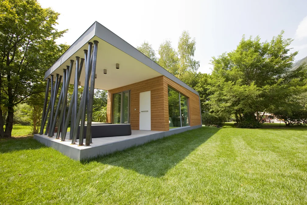 Casa moderna eco-sostenibile con ampia vetrata e giardino verde.