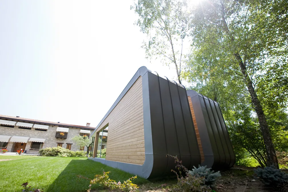 Vista laterale di una casa moderna con rivestimento in legno e ampie finestre.