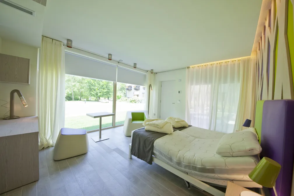 Interno luminoso di una camera da letto moderna con vista sul giardino.