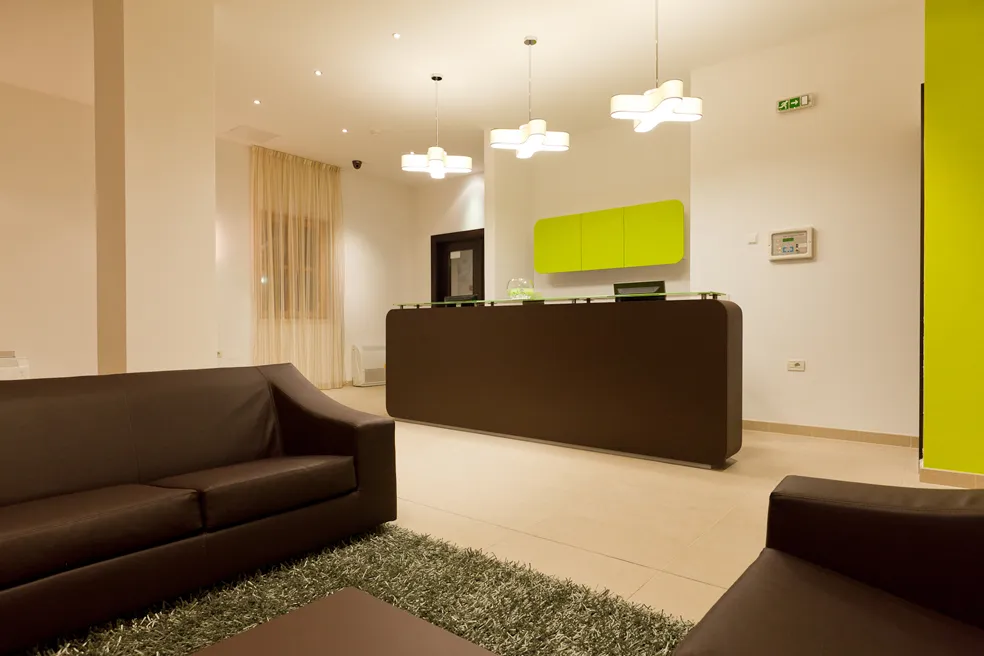 Area reception moderna dell'hotel con arredamento verde e marrone e lampadari.