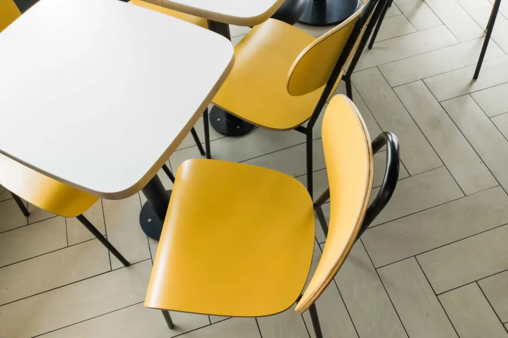 Tavolo con sedia gialla moderna in un ambiente luminoso e pavimento in parquet chiaro.